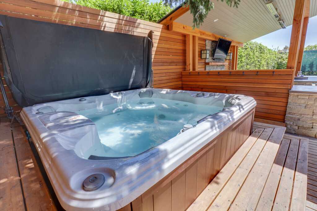 Outdoor hot tub on wooden deck with covered patio