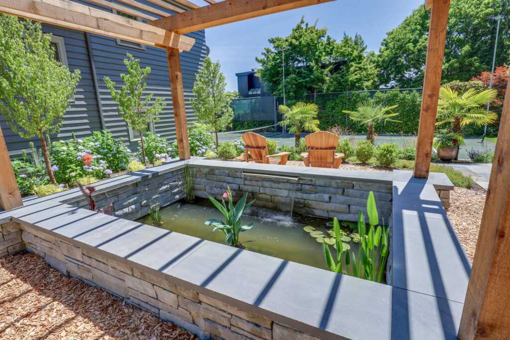 Landscaped backyard with pond and wooden chairs