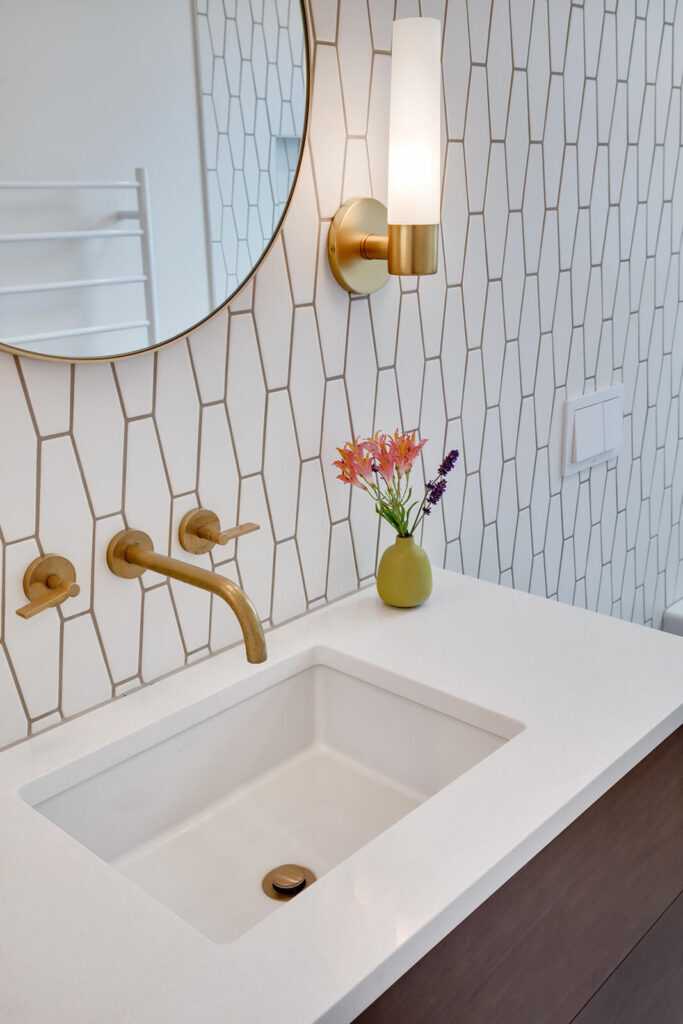 Modern bathroom sink with geometric tiled wall and flowers