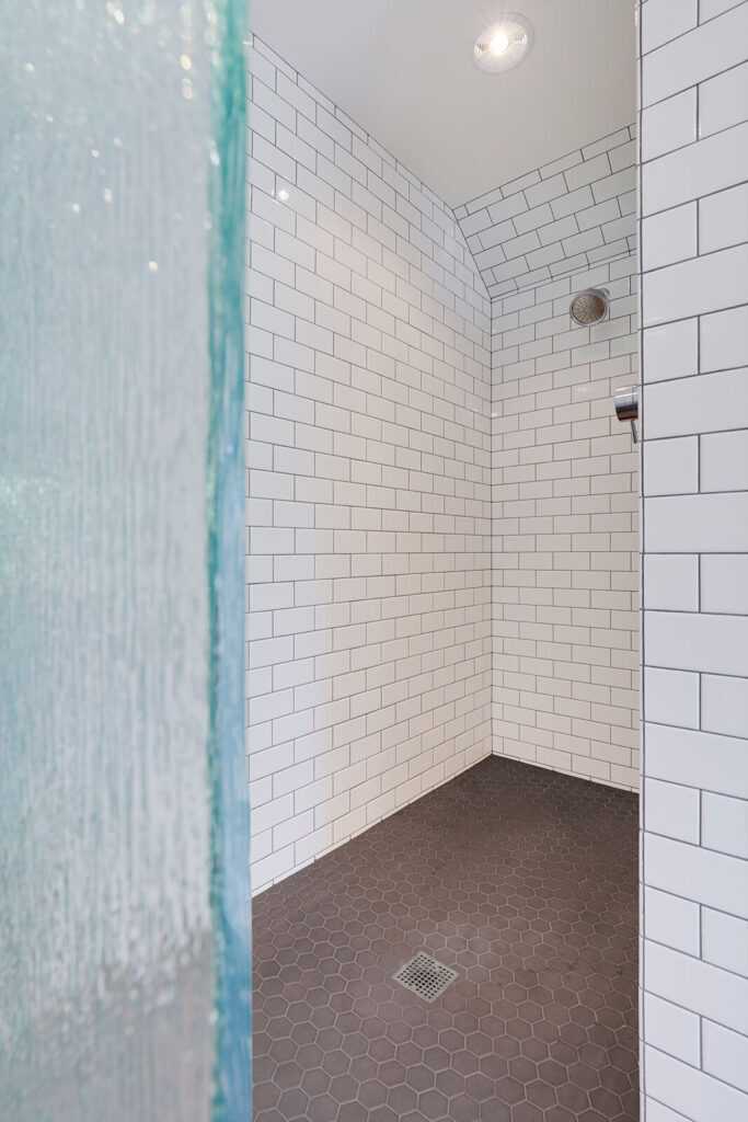 Modern shower with white subway tiles and dark floor