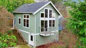 Green two-story house with balcony surrounded by trees