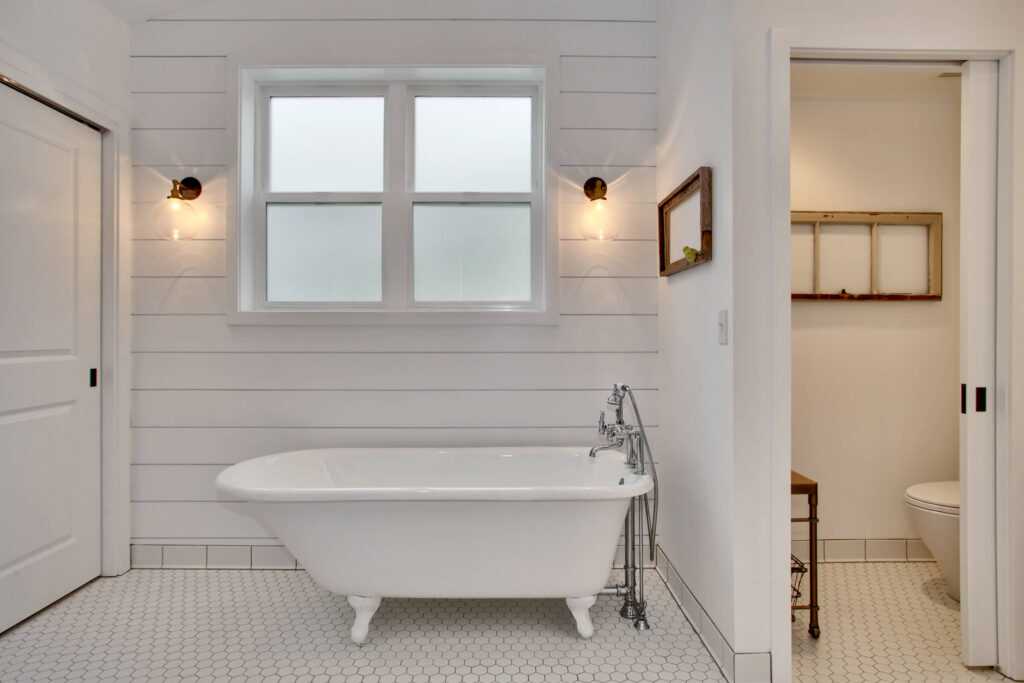 Bright bathroom with clawfoot tub and white tiled floor