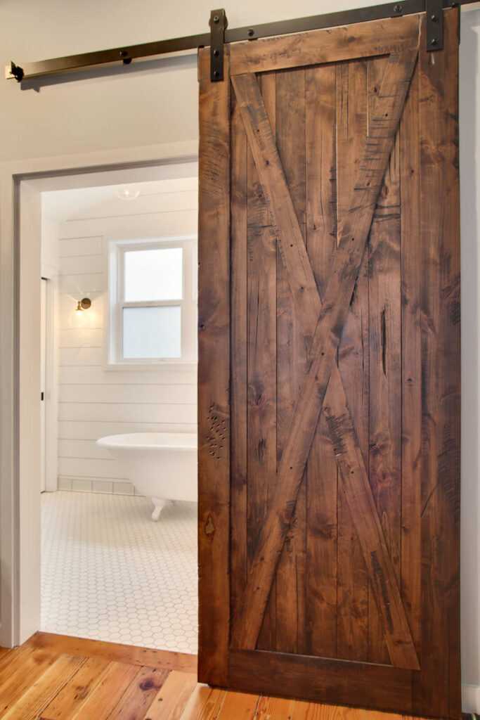 Rustic wooden sliding barn door leading to bathroom