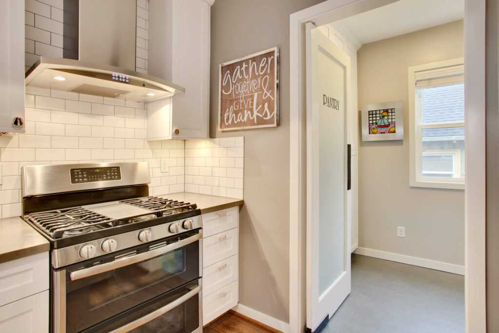 Modern kitchen with stove, white tiles, and pantry door