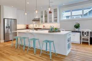 Modern kitchen with white cabinets and teal bar stools