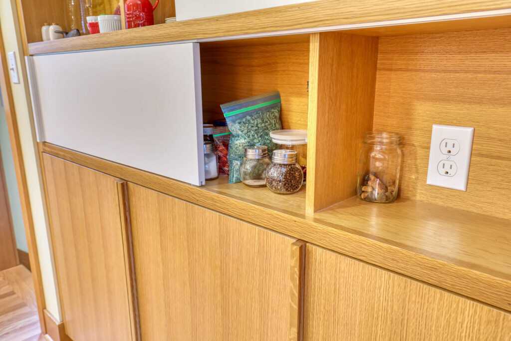 Wooden kitchen shelf storing spices and jars