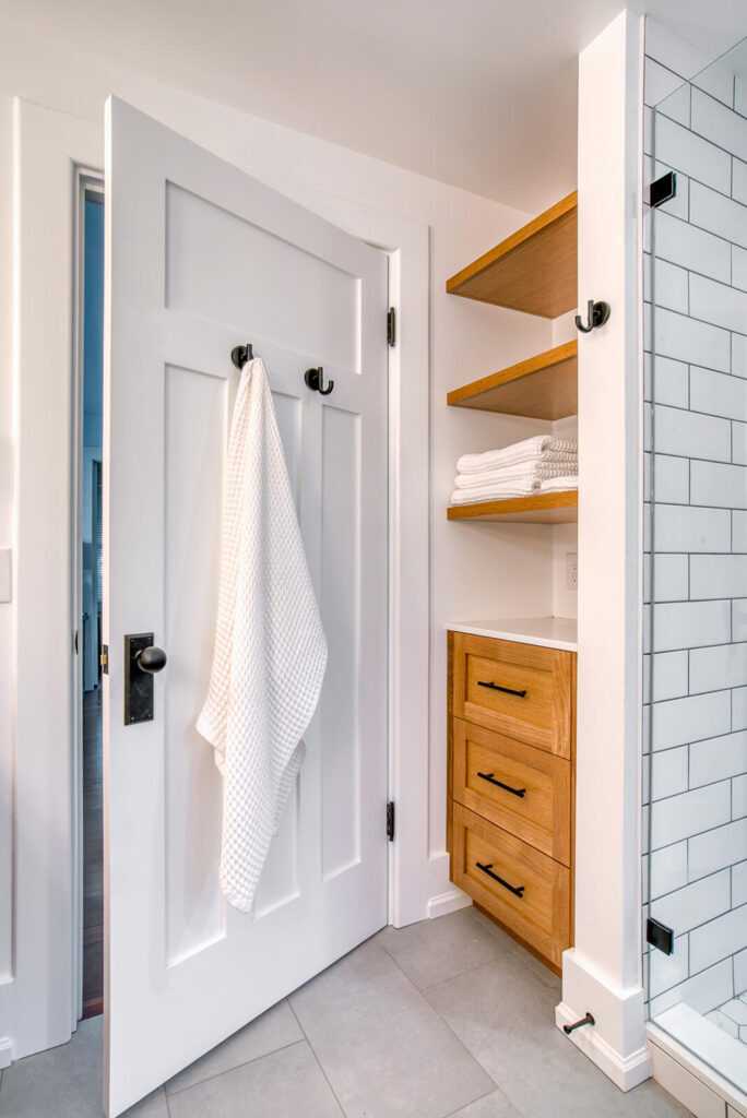Modern bathroom with white door and wooden storage