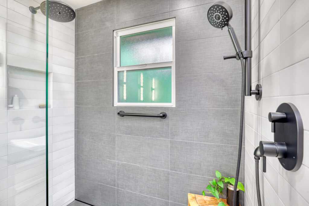 Modern shower with window and black fixtures.