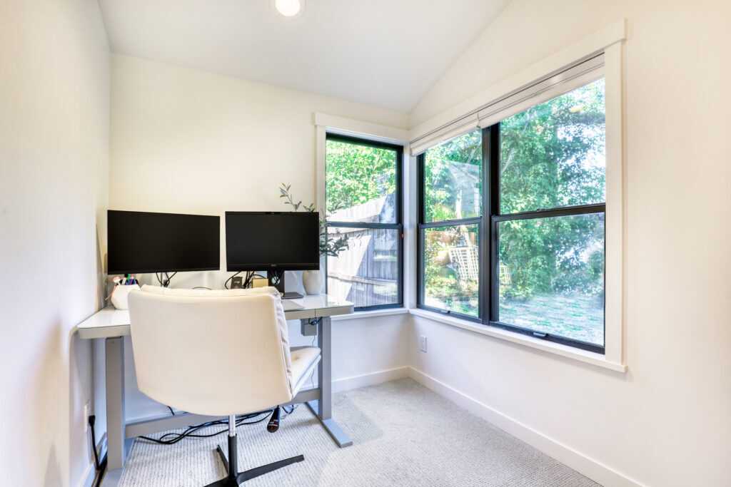 Bright home office with two monitors and garden view.
