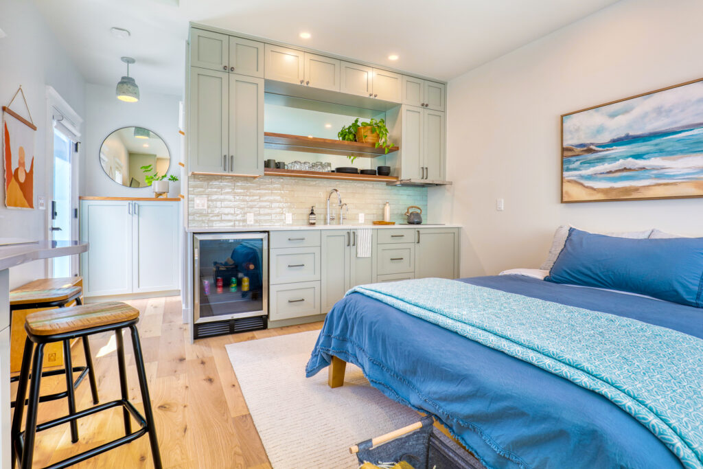 Guest suite with sage green cabinetry, built-in kitchenette, and beverage fridge — every detail considered when the design build process is explained and executed as one.