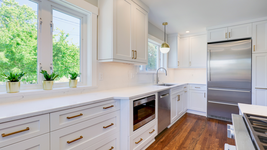 Kitchen remodel Seattle with white shaker cabinets, brass hardware, stainless appliances, and dark hardwood floors.