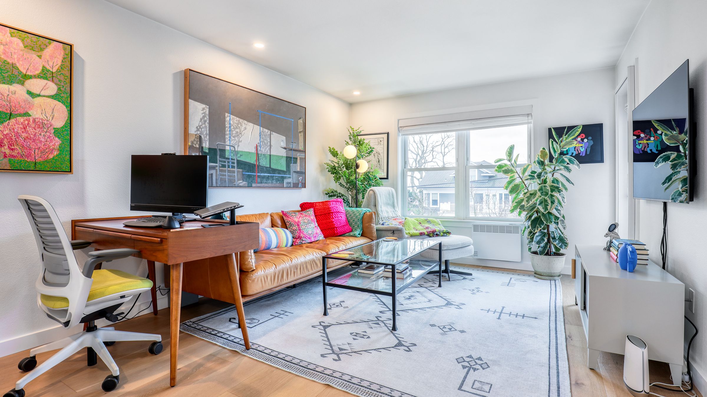 Living area with a walnut desk, tan leather sofa and colorful artwork in a Queen Anne home remodel.